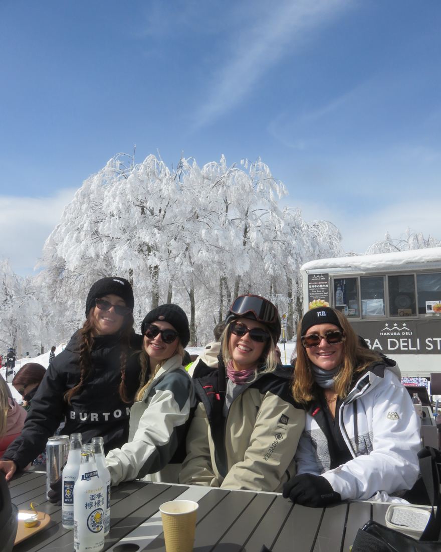 Four friends smiling at a snowy lunch spot in Japan